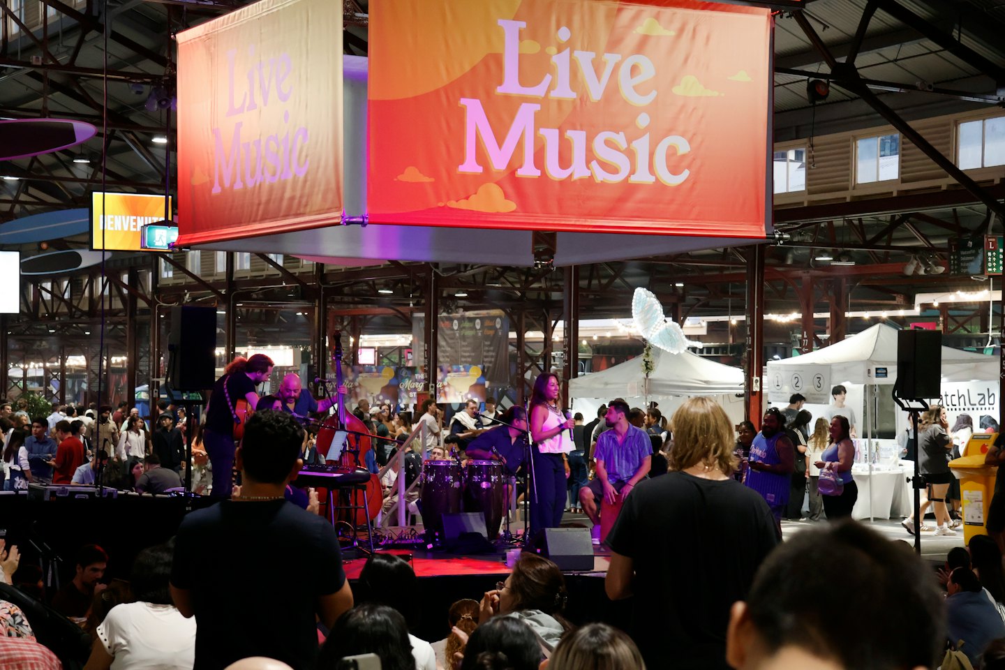 Musicisti si esibiscono dal vivo sul palco davanti a un pubblico numeroso.