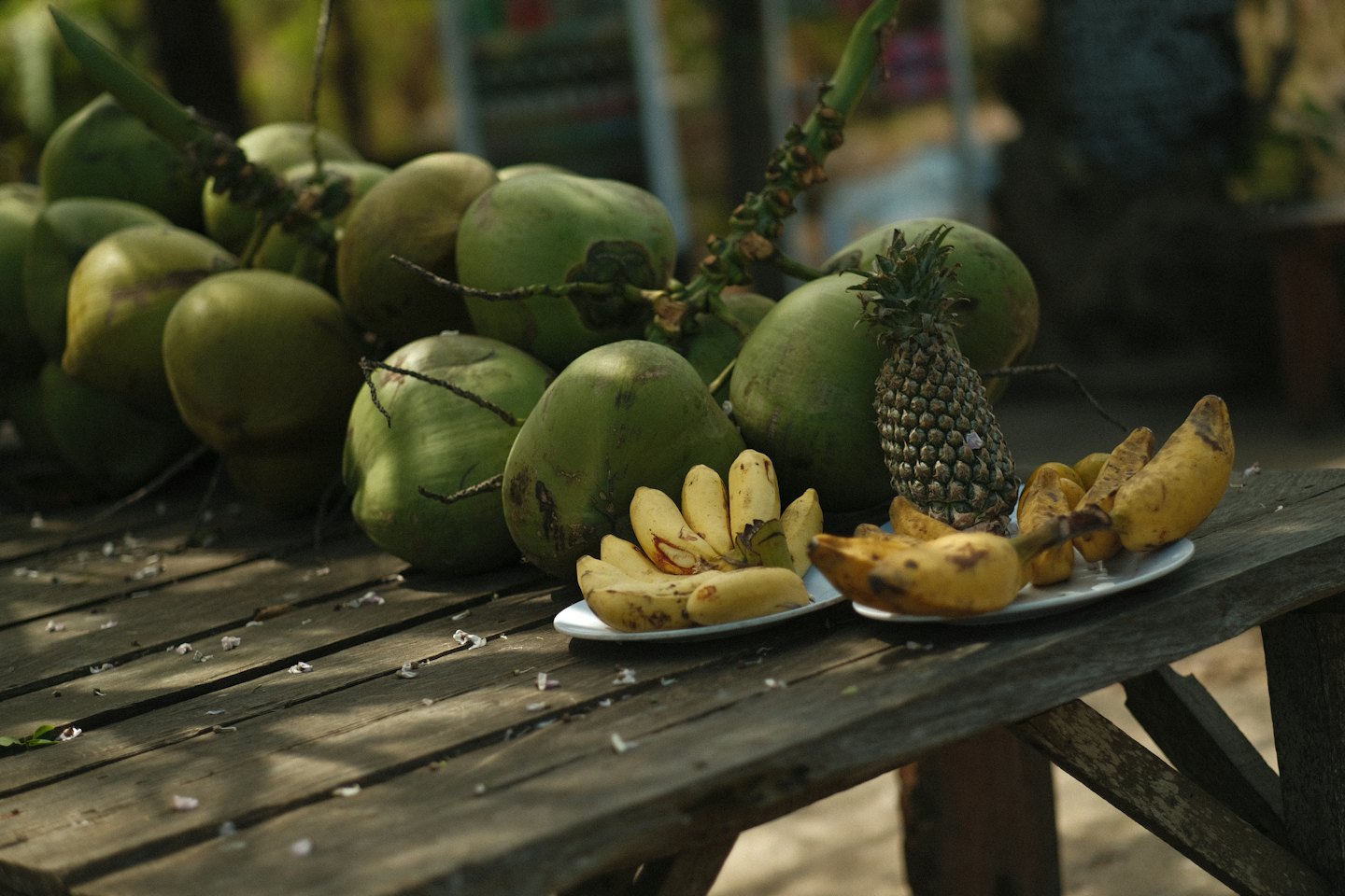 Noci di cocco verdi e banane disposte su un tavolo di legno.