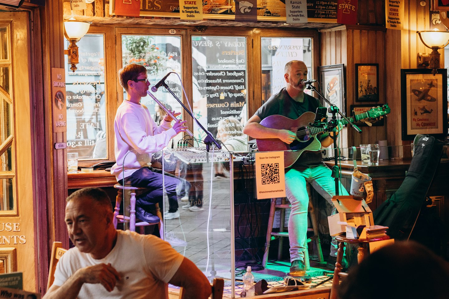 Due musicisti si esibiscono con musica acustica per un pubblico in un pub.