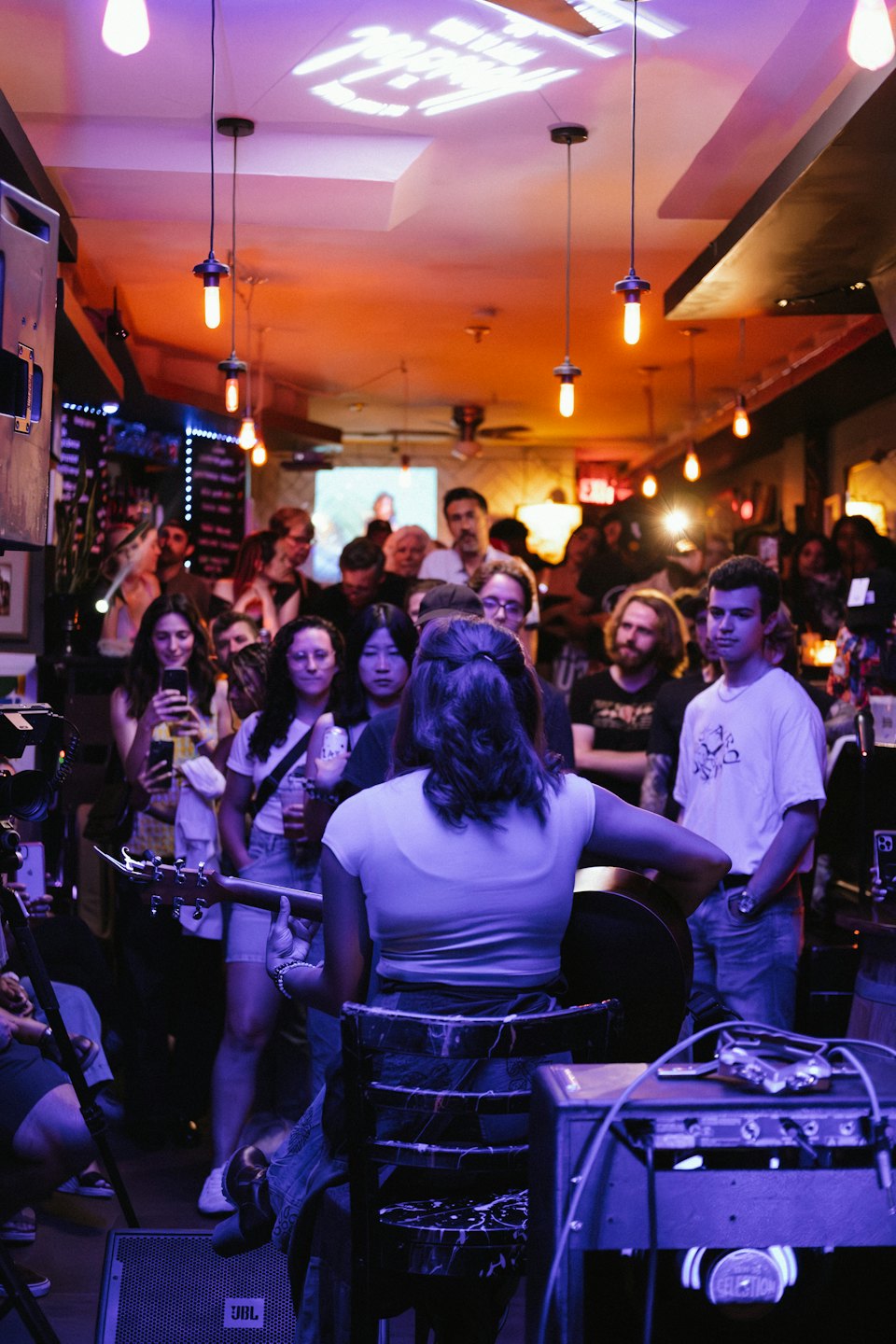 Musicista che suona la chitarra acustica per un pubblico in un bar.