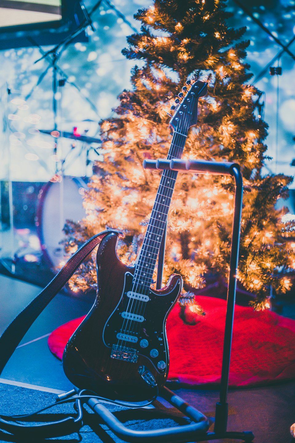 Una chitarra elettrica poggia su un supporto vicino a un albero di Natale.