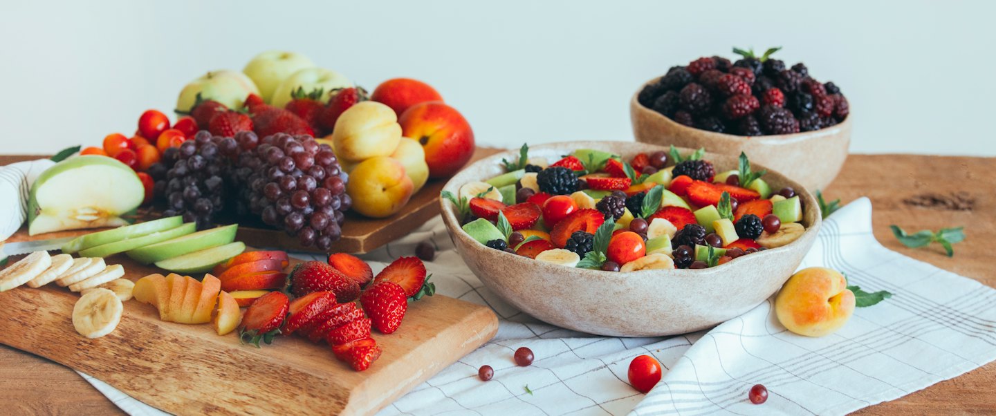 Assortimento di frutta fresca in ciotole e su un tagliere.