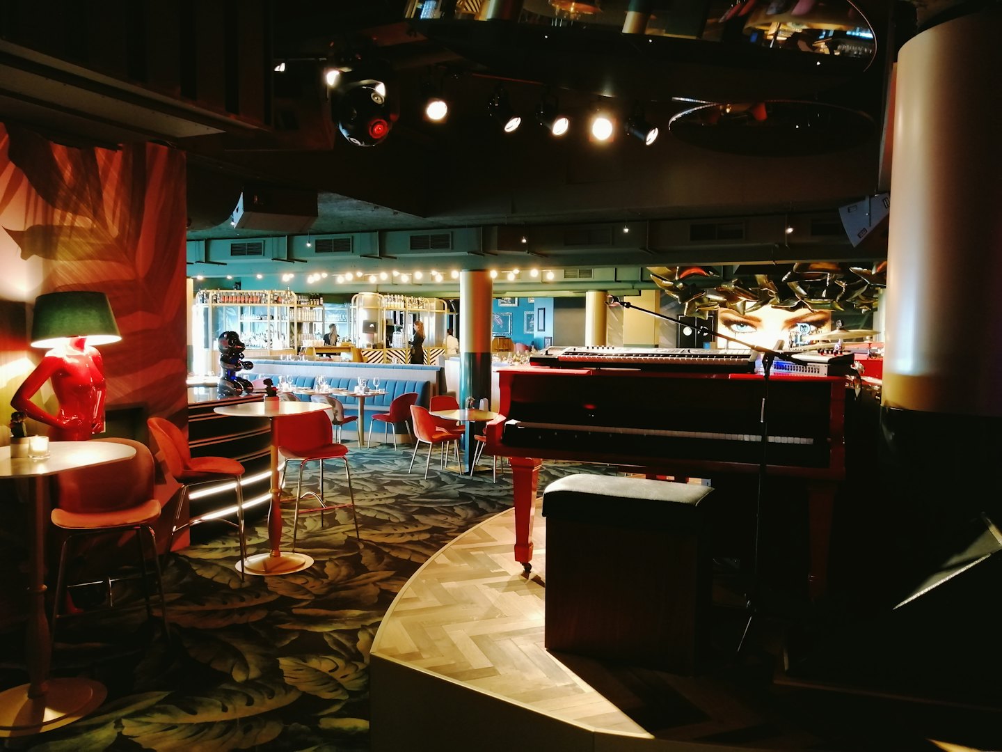 Allestimento per musica dal vivo con pianoforte rosso su un palco di legno in un lounge.
