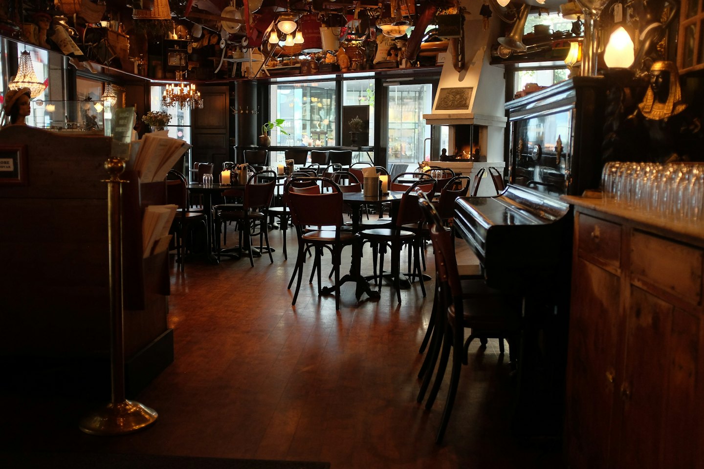 Interno di un ristorante vuoto con tavoli in legno e un pianoforte a coda.