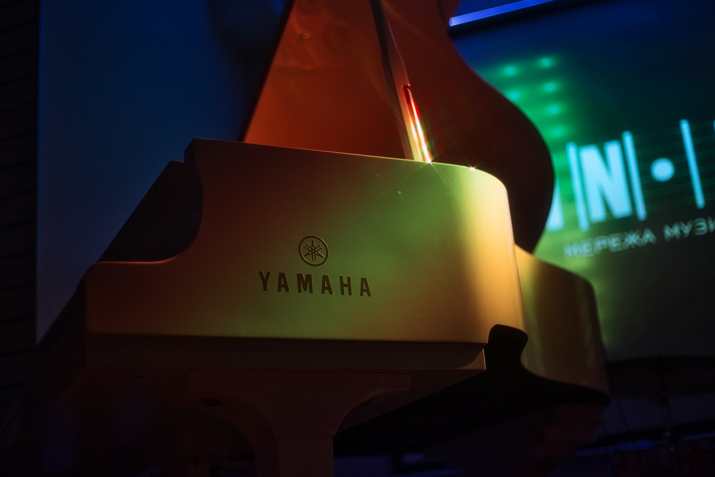 Un pianoforte a coda bianco si trova su un palco.